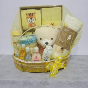 Yellow baby hamper by Gin Thye with Muji baby gift set, Johnson baby products, and premium cotton swaddle arranged in a yellow oval basket